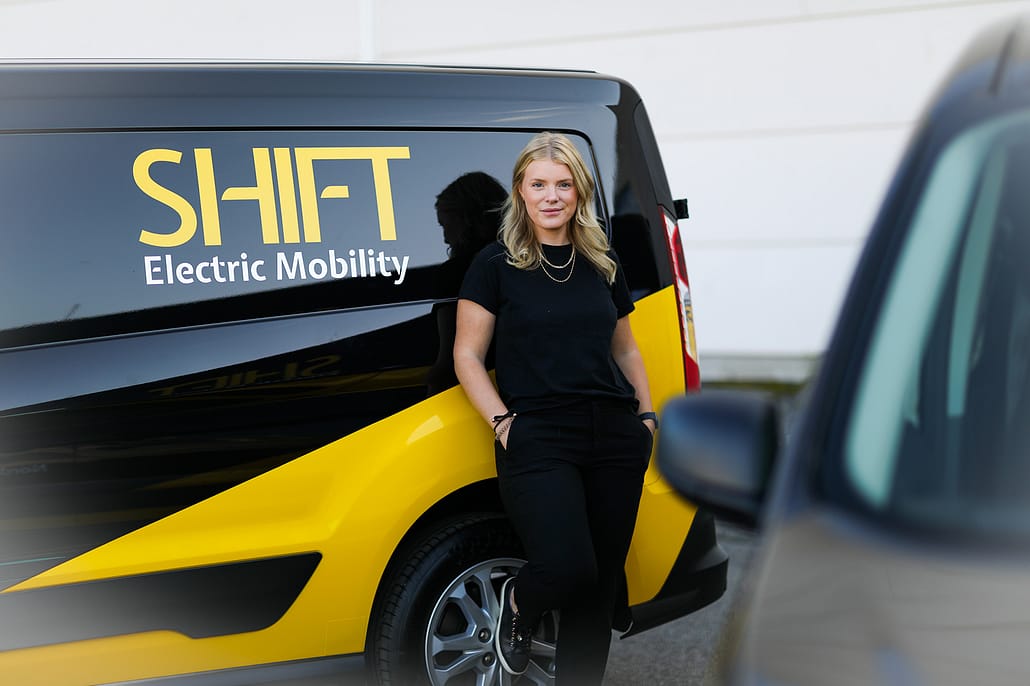 Woman in front of SHIFT Electric Mobility vehicle.